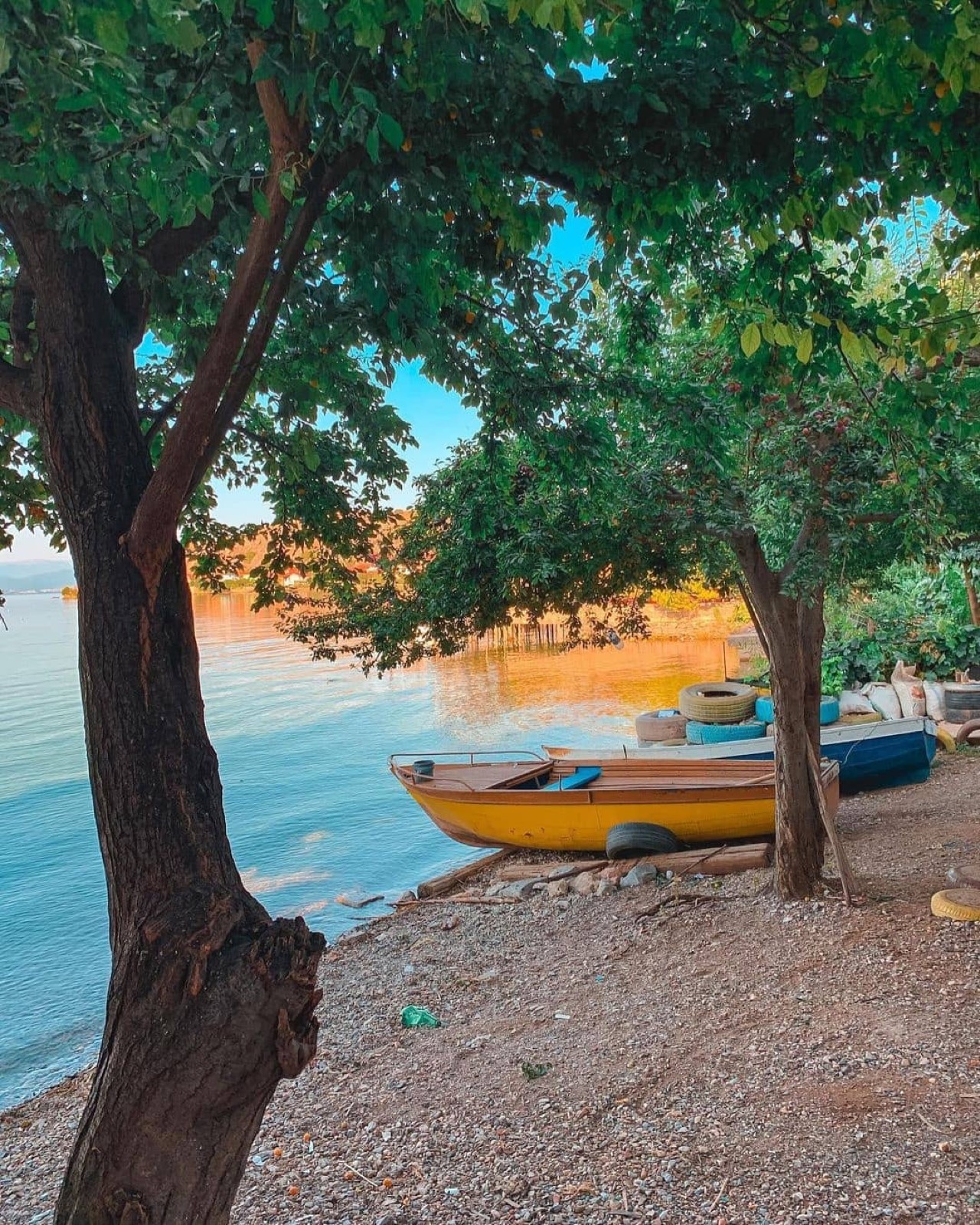 Wooden boats on a tranquil Albanian lakeshore at golden hour